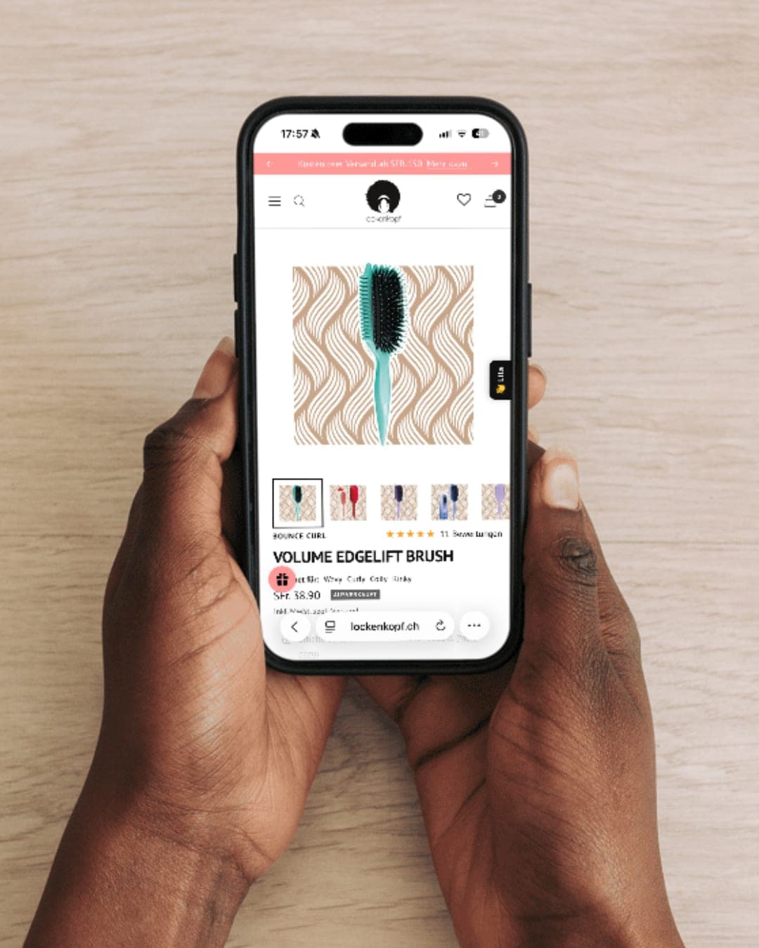 Mobile Produktübersicht von Lockenkopf Hand hält ein Smartphone mit der Produktübersicht des Lockenkopf Onlineshops