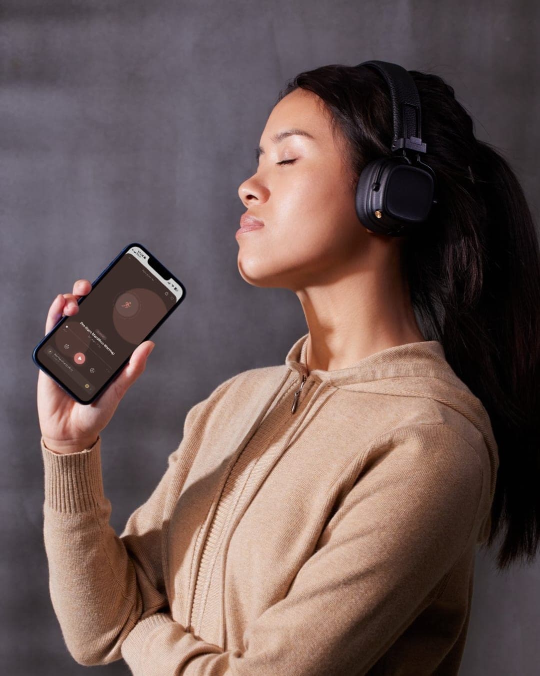 Warm-up-Anleitung über die Warmup.today App Frau nutzt die Warmup.today App mit Kopfhörern auf ihrem Smartphone